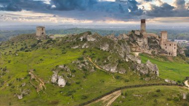 Polonya 'nın Çek Cumhuriyeti yakınlarındaki Olsztyn Kalesi' nin insansız hava aracı görüntüsü sıcak altın saat ışığıyla aydınlatılıyor. Jura Krakowsko-Çekoslovakya manzarasında küçük bir kasabanın üzerinde yükselen ortaçağ kireçtaşı kalesi.