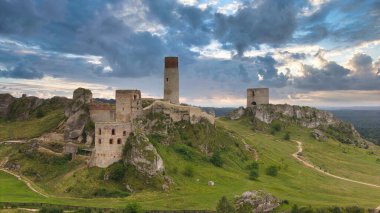 Polonya 'nın Çek Cumhuriyeti yakınlarındaki Olsztyn Kalesi' nin insansız hava aracı görüntüsü sıcak altın saat ışığıyla aydınlatılıyor. Jura Krakowsko-Çekoslovakya manzarasında küçük bir kasabanın üzerinde yükselen ortaçağ kireçtaşı kalesi.