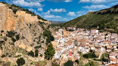 İspanya 'daki Chulilla' nın insansız hava aracı görüntüsü dramatik kireçtaşı kanyon kayalıklarının arasına kurulmuş bir dağ köyünü gösteriyor. Terracotta çatılarının, nehir vadisinin ve etrafındaki dağların detaylı manzarası.