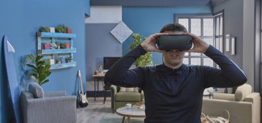 Sanal gerçeklik gözlüklü, dekoratif mavi duvar arka planlı bir adam..