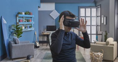 Sanal gerçeklik gözlüklü, dekoratif mavi duvar arka planlı bir adam..