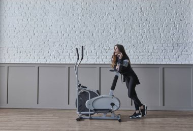 Kadın ev konsepti üzerine spor yapıyor, cep telefonu içme suyu ile konuşuyor, dekoratif arka plan tarzı iç mekan tarzı..