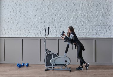 Kadın ev konsepti üzerine spor yapıyor, cep telefonu içme suyu ile konuşuyor, dekoratif arka plan tarzı iç mekan tarzı..