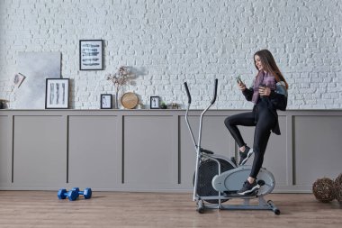 Kadın ev konsepti üzerine spor yapıyor, cep telefonu içme suyu ile konuşuyor, dekoratif arka plan tarzı iç mekan tarzı..
