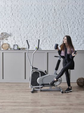 Kadın ev konsepti üzerine spor yapıyor, cep telefonu içme suyu ile konuşuyor, dekoratif arka plan tarzı iç mekan tarzı..