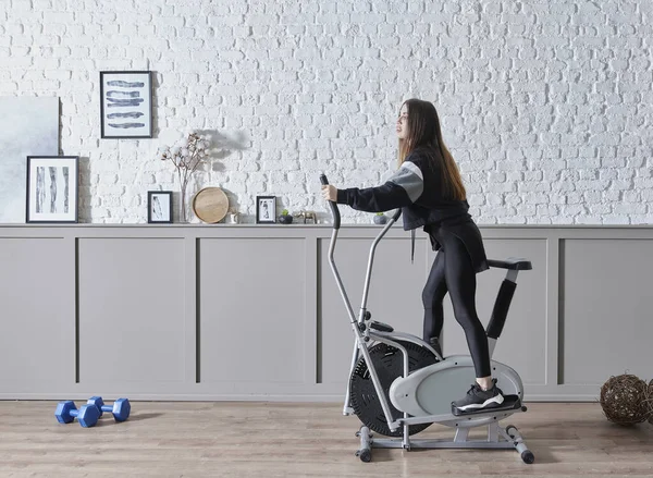 Training sportive woman at home, doing sport interior concept, decorative background and ride a bike style.