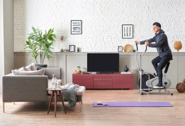Adam evde spor yapıyor, formda erkek eğitim tarzı, dekoratif oturma odası, tuğla duvar kanepesi ve televizyon tarzı..