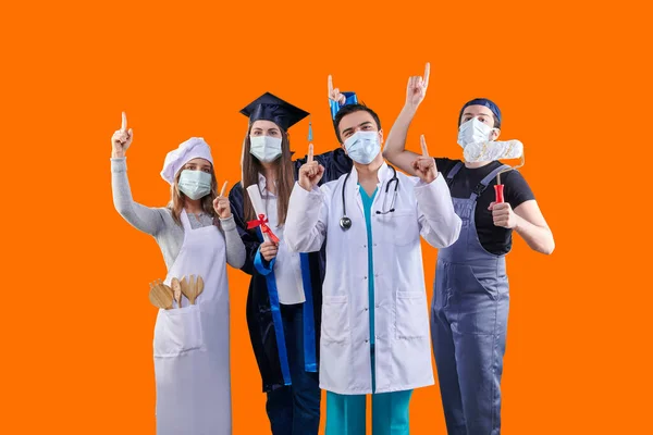 Chef, Graduated girl, doctor and painter man, group of various profession in pandemic and wear mask, colorful background. They are showing up them finger.