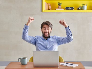 Kazanan dizüstü bilgisayarın önünde mutlu bir şekilde kulaklık takıyor..