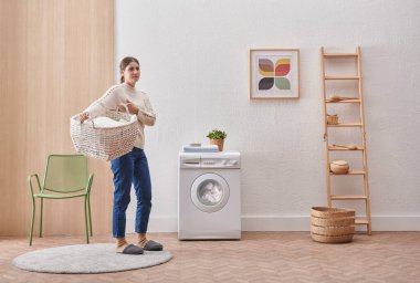 Laundry room washing machine and dirty clothes decorative modern style. Woman is keeping clothes basket.