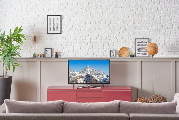 Watching television in the room close up grey sofa and white brick wall, frame lamp concept.