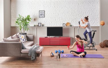 Two girl friends are doing training and sport at home, taking a photo of yourself style.