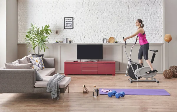 Sportive woman is doing training at home, purple mat, blue dumbbell, decorative living room concept. Healthy lifestyle.
