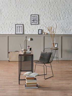 Çalışma odası ahşap masa dizüstü bilgisayarı, metal siyah koltuğu, poster tuğlası duvarı..