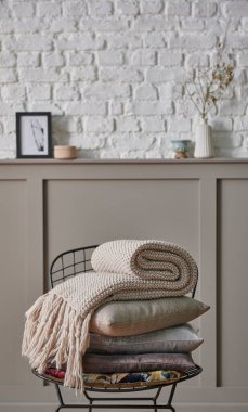 Siyah metal koltukta yastık ve battaniye katlanır, klasik kahverengi duvar ve beyaz tuğla arka plan ev eşyası hala yaşam konsepti.