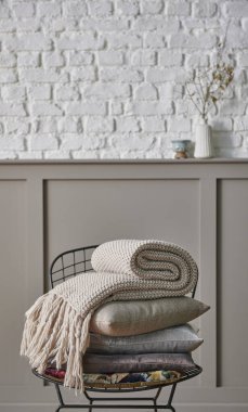 Siyah metal koltukta yastık ve battaniye katlanır, klasik kahverengi duvar ve beyaz tuğla arka plan ev eşyası hala yaşam konsepti.