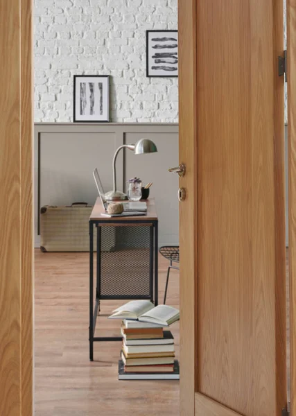 Close up wooden door, working room at home style with wooden table laptop and metal black chair, poster brick wall.