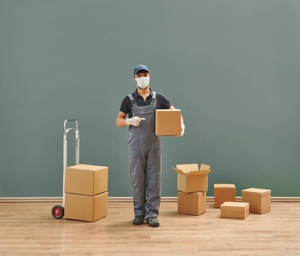 Delivery man is pointing out up and box, transportation cardboard box in the room.