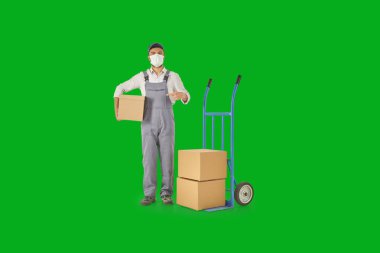 Teslimatçı ve taşıyıcı elinde karton kutu ve mavi renkli bir kamyonet tutuyor..