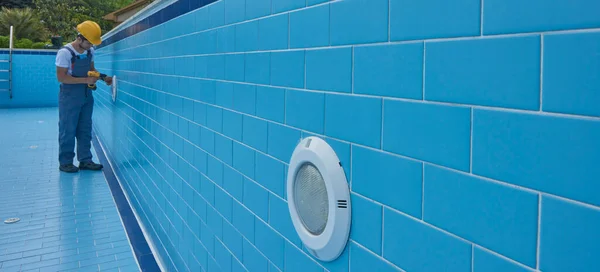 Tamirci ekipmanla havuzu tamir ediyor. Havuz bakım biçimi.