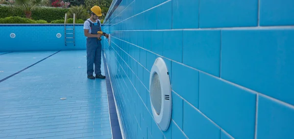 Tamirci ekipmanla havuzu tamir ediyor. Havuz bakım biçimi.