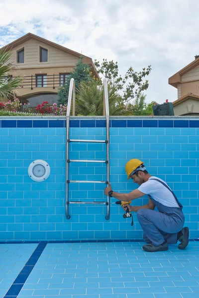 Tamirci ekipmanla havuzu tamir ediyor. Havuz bakım biçimi.