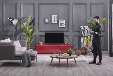 Adam modern oturma odasında iyi vakit geçiriyor, gri taş duvar arka planı, çerçeve konsepti ve televizyon stili..