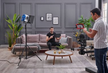 Promosyon temsilcisi yüksek kaliteli ışık ve kamera ile arka planda video çekiyor..
