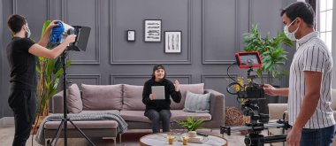 Promosyon temsilcisi kadın, yüksek kaliteli ışık ve kamera ile arka plan tarzıyla evde video çekiyor.