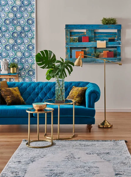 Blue classic sofa furniture home design, gold lamp and middle table, wooden palette bookshelf, vase of green plant and home accessory style,interior decor.