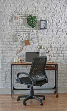 Tuğla duvar, sandalye, dizüstü bilgisayar ve ofis tarzı dekoratif çalışma odası. Lamba stili ahşap masa.