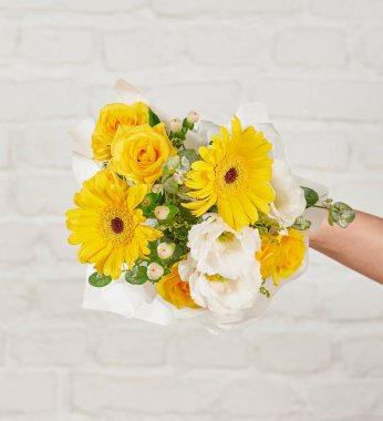 Güzel çiçek aranjmanları: portakal ve beyaz güllerden oluşan bir buket ve beyaz bir duvara karşı dekoratif çizgili bir kutuda pembe bir lale düzeneği..