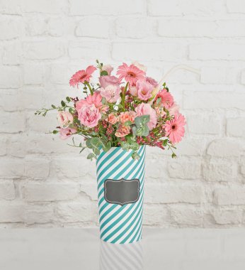 Güzel çiçek aranjmanları: portakal ve beyaz güllerden oluşan bir buket ve beyaz bir duvara karşı dekoratif çizgili bir kutuda pembe bir lale düzeneği..