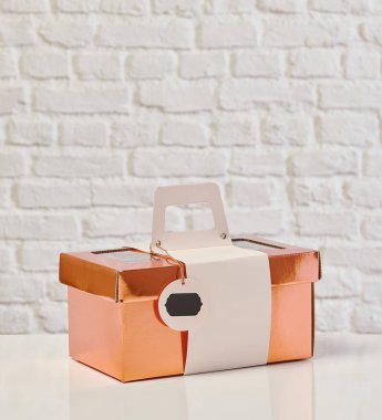 Güzel çiçek aranjmanları: portakal ve beyaz güllerden oluşan bir buket ve beyaz bir duvara karşı dekoratif çizgili bir kutuda pembe bir lale düzeneği..