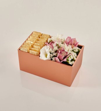 Güzel çiçek aranjmanları: portakal ve beyaz güllerden oluşan bir buket ve beyaz bir duvara karşı dekoratif çizgili bir kutuda pembe bir lale düzeneği..