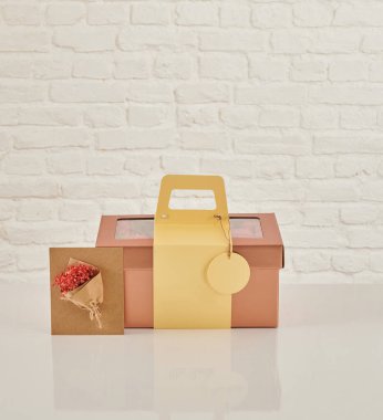 Güzel çiçek aranjmanları: portakal ve beyaz güllerden oluşan bir buket ve beyaz bir duvara karşı dekoratif çizgili bir kutuda pembe bir lale düzeneği..