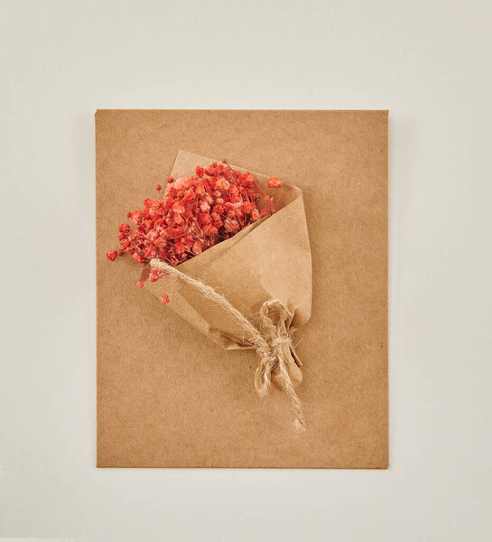 Красивые цветочные композиции: ручной букет оранжевых и белых роз, и розовый тюльпан расположение в декоративной полосатой коробке против белой кирпичной стены.