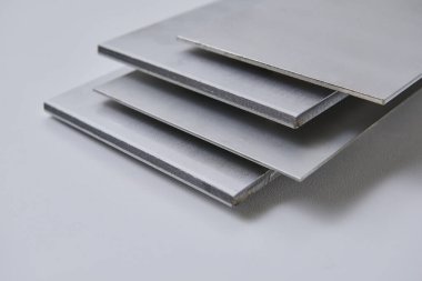 Metalik yüzey levhalarının görüntüsünü fırçalanmış ve mat bitkileriyle kapatın, mimari, imalat ve ürün tasarım uygulamaları için modern malzeme tasarımı ve endüstriyel dokular sergileniyor. İzole edilmiş beyaz arkaplan.