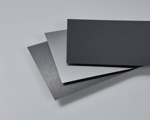 Close up image of metallic surface sheets with brushed and matte finishes, showcasing industrial texture and modern material design for architecture, manufacturing, and product design applications. Isolated white background.