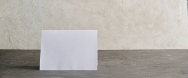 Tarafsız bir zemin üzerinde duran boş katlanmış bir kartın olduğu minimalist modelleme sahnesi, davetiyeleri göstermek için ideal, tebrik kartı tasarımları, markalaşma veya promosyon şablonları.