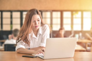 İşyerindeki masasında dizüstü bilgisayar kullanan genç bir kadın.