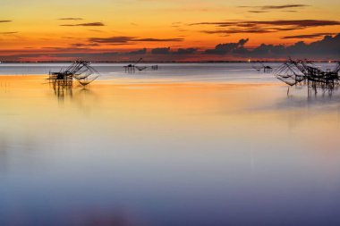 Güneşin doğuşu, Baan Pak Pra 'daki dev ağlar Thale Noi Wetlands ile avlanmak Tayland' ın Phatthalung şehrinin ünlü bir simgesidir..