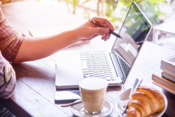 A man using laptop computer with cup coffee and bread on the table, Looking for direction and inspiration.