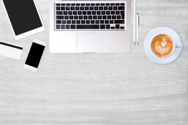 Laptop bilgisayarı, akıllı telefon, defter ve kahve dolu modern beyaz ofis masası. Çalışma masası kavramı. Fotokopi alanı olan üst görünüm, düz yatış.