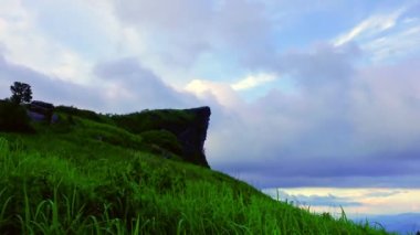 4K zaman atlaması, gökyüzünde hareket eden güzel bulutlar ve arka planda Phu Chi Fa ile hareket eden çimenler. Phu Chi Fa Ulusal Parkı Tayland 'ın Chiang Rai şehrinde ünlü bir turizm merkezidir..