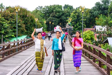 KANCHANABURI, THAILAND, ECTOBER 5 Ekim 2017: Etnik olmayan bir kadın yürür ve kafasında eşyalar taşır ahşap bir köprüde yürür, Mon köyündeki en uzun tahta köprü, Sangklaburi, Kanchanaburi, Tayland