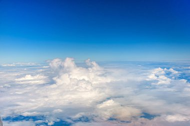 Bulutlar mavi gökyüzü manzarasına karşı bir uçak penceresinden arka plan için. Bulutların üstünde, havada uçuyor.