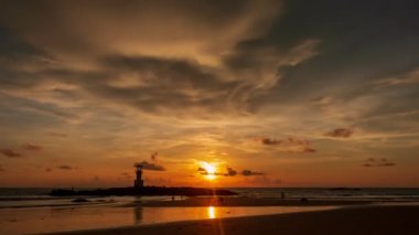 4K zaman atlaması, Khao Lak Light Beacon 'ın gün batımındaki siluetinin manzarası Nang Thong Sahili, Phang Nga, Tayland' daki dramatik alacakaranlık gökyüzü. Deniz fenerinin siluetleri parlak turuncu bir günbatımı gökyüzünde