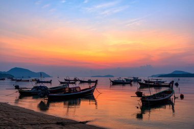 Tayland 'ın Phuket Adası' ndaki Rawai Sahili 'nde balıkçı tekneleri ile güzel bir gün doğumu manzarası. Sahilde gün doğumuyla birlikte bir balıkçı teknesi..