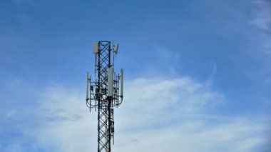 4K zaman atlaması, mavi gökyüzü arka planında hareket bulutları olan Telekomünikasyon kuleleri. Mavi gökyüzü beyaz bulutları hareket halindeki kule sinyalinin zaman aşımına uğramış görüntüsü